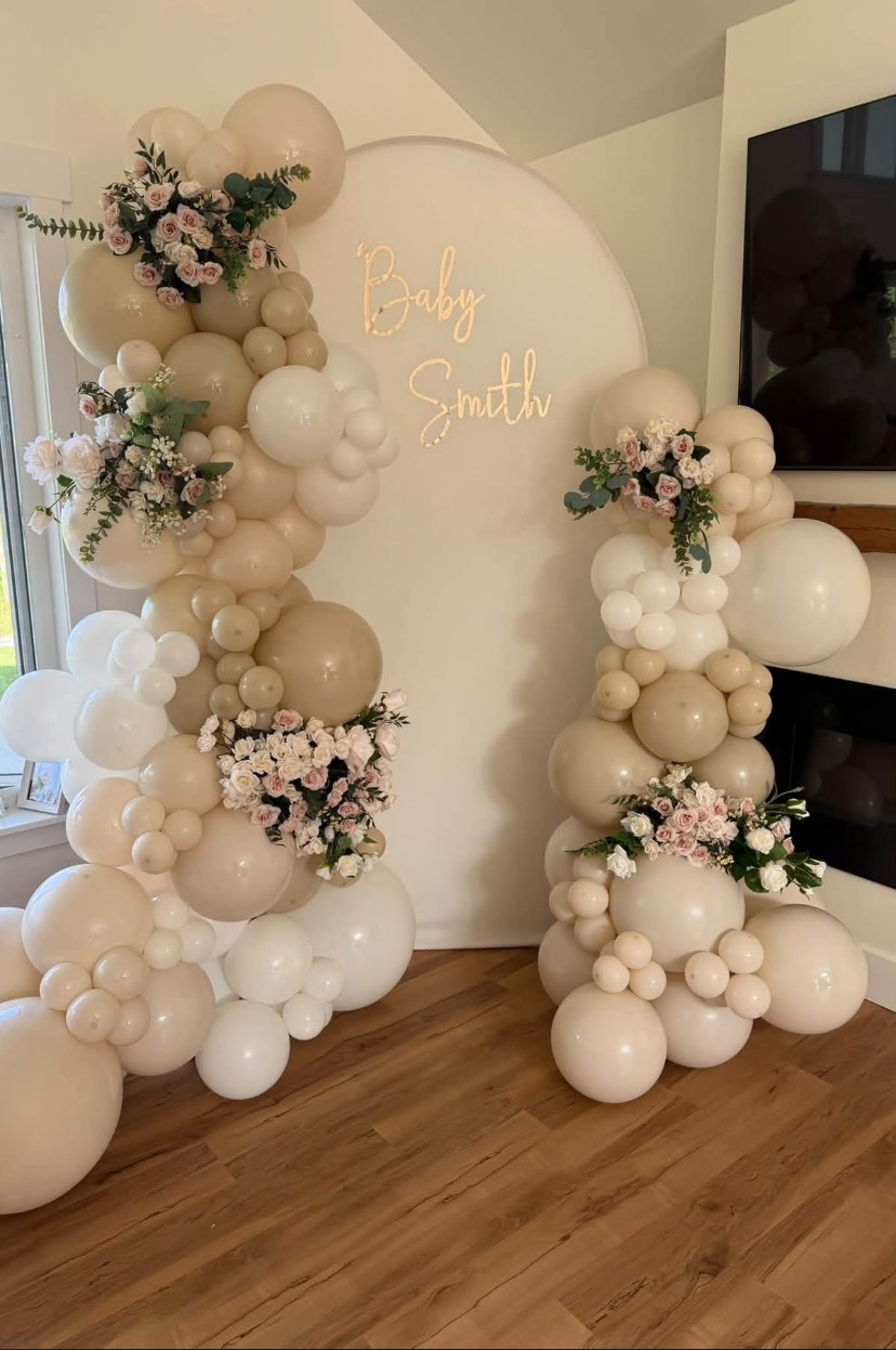 Cream and white balloon display with flowers for a baby shower