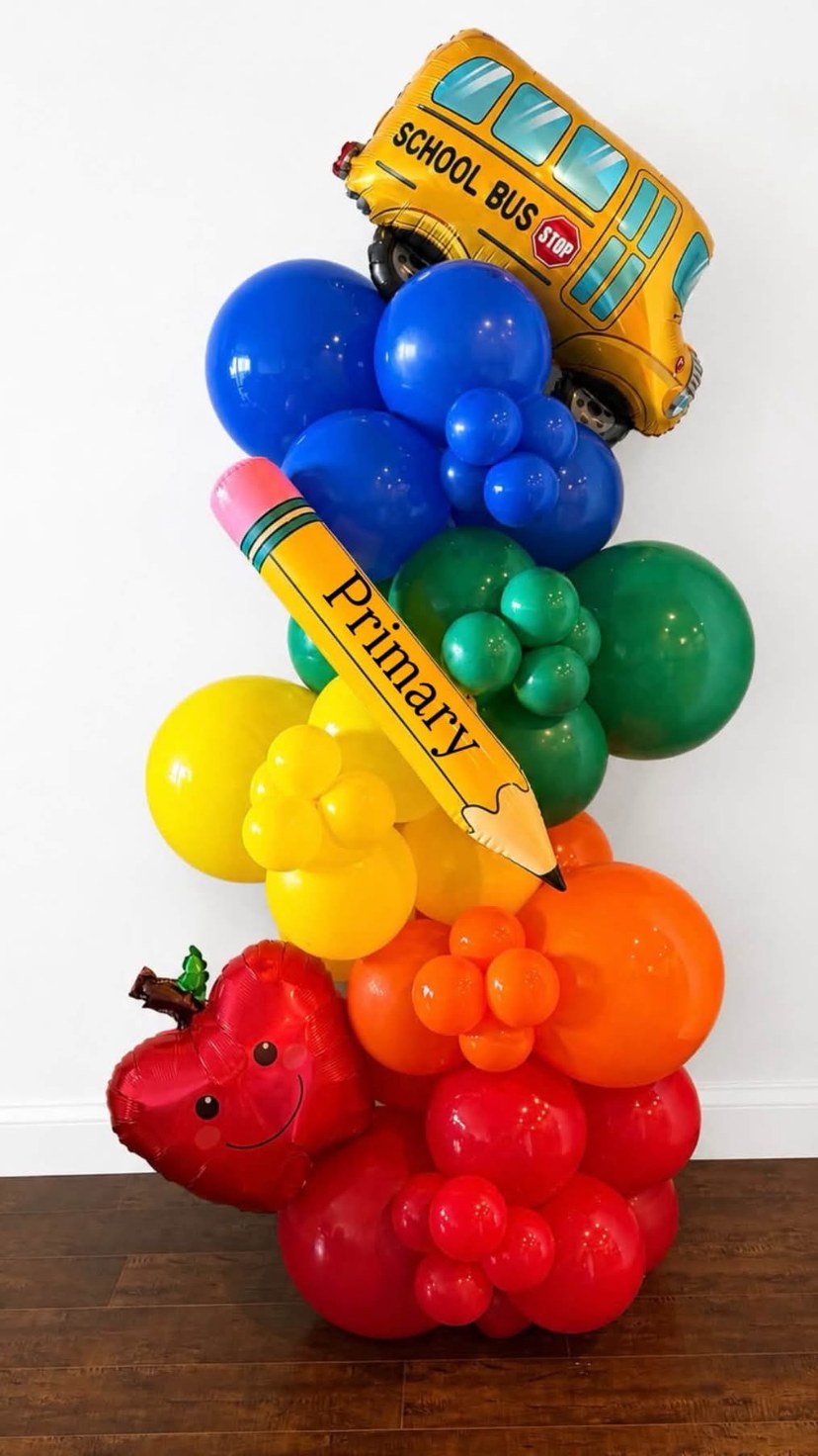 Colourful school-themed balloon arrangement with a school bus and pencil