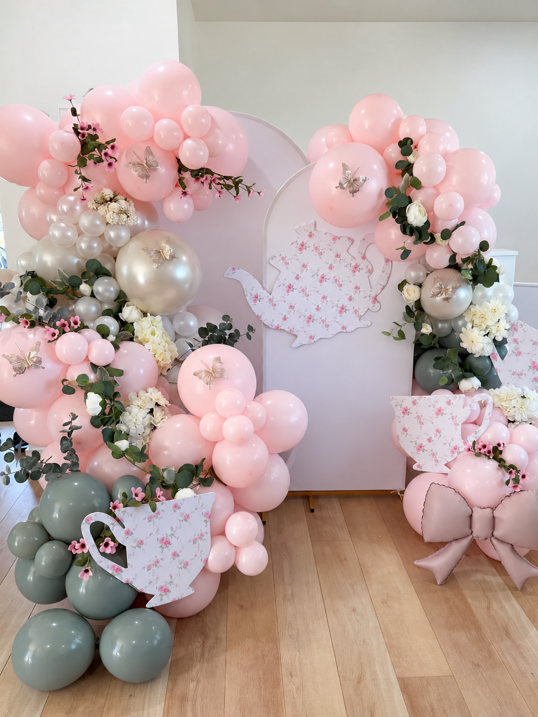 Blush pink balloons with floral details and a tea-themed backdrop